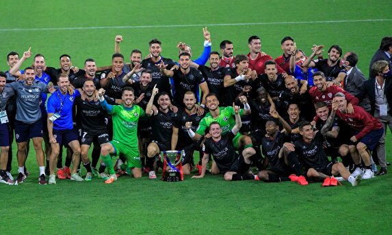 Los jugadores del Huesca posan con el trofeo de campeones de LaLiga SmartBank sobre el césped de El Molinón. | EFE