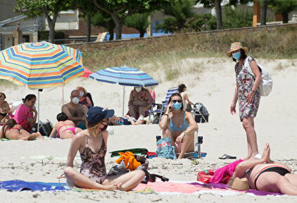Varias personas protegidas con mascarillas toman el sol en la Playa de A Rapadoira en Foz, en la comarca de A Mariña, Lugo | Carlos Castro / Europa Press