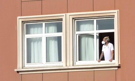 El jugador del Fuenlabrada, Chico Flores, se asoma a una ventana del hotel Finisterre donde permanecen confinados. | EFE