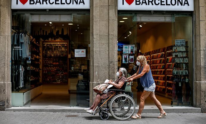 Dos personas pasan por una tienda de recuerdos en las Ramblas de Barcelona. | EFE