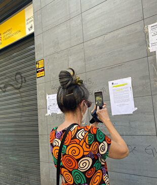 Una mujer fotografía uno de los carteles colocados en la fachada de una oficina del SEPE I Europa Press