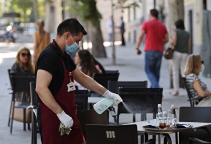 Un camarero desinfecta una mesa tras las marcha de los clientes en la terraza de un bar del centro de Madrid. | EFE