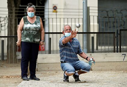Dos personas protegidas con su mascarilla juegan a la petanca este domingo. | EFE