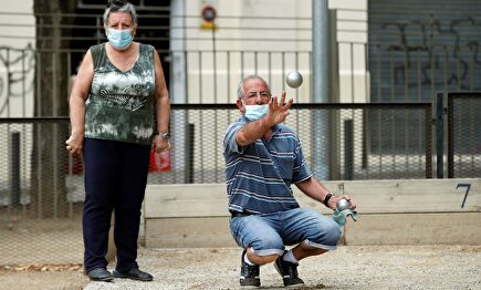 Dos personas protegidas con su mascarilla juegan a la petanca este domingo. | EFE
