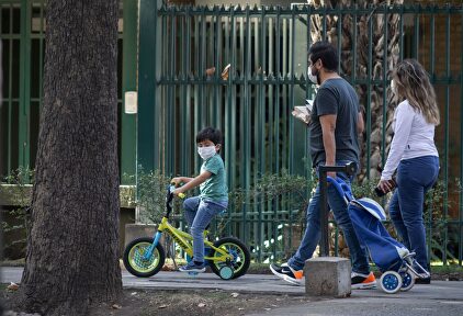 Una familia de paseo con mascarillas | Alamy