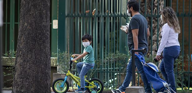 Una familia de paseo con mascarillas | Alamy