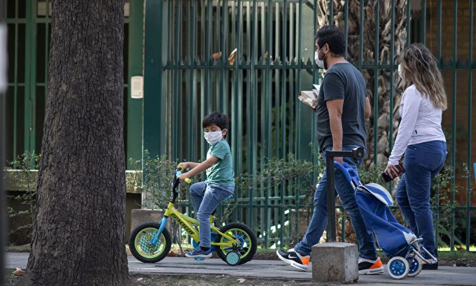 Una familia de paseo con mascarillas | Alamy