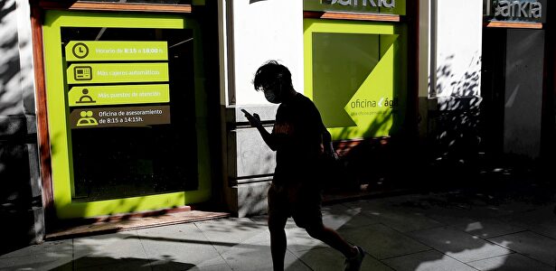 Una persona camina por el centro de Madrid delante de una sucursal de Bankia. | EFE