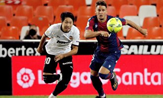El delantero coreano del Valencia CF Kang-In Lee persigue el balón con el serbio Nemanja Radoja, del Levante. | EFE