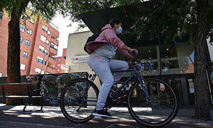 Una vecina pasa en bici por delante del centro de salud García Noblejas, en el distrito madrileño de Ciudad Lineal, este viernes. | EFE