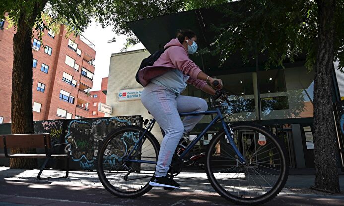 Una vecina pasa en bici por delante del centro de salud García Noblejas, en el distrito madrileño de Ciudad Lineal, este viernes. | EFE