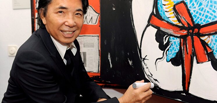 El diseñador Kenzo Takada firma una de sus pinturas. | EFE