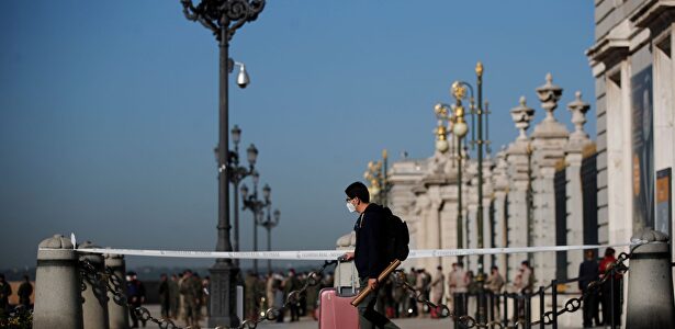 Un joven con su maleta pasa ante el Palacio Real de Madrid | EFE
