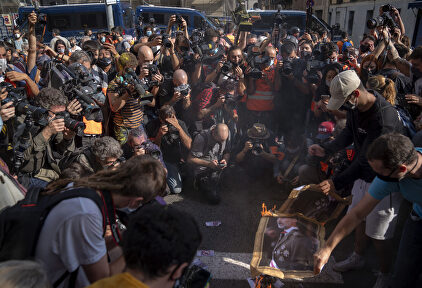 Imagen en la que se ve apenas un par de 'personas quemando una imagen del Rey rodeados de decenas de fotógrafos. (AP Photo/Emilio Morenatti) | Gtres