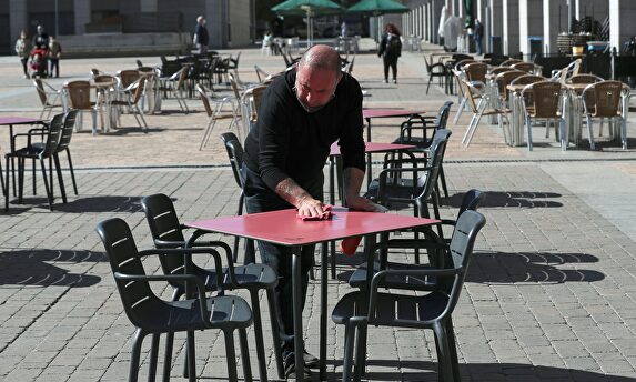 Un camarero desinfecta una de las mesas de la terraza de un bar en la Plaza Mayor de la localidad madrileña de Leganés | EFE