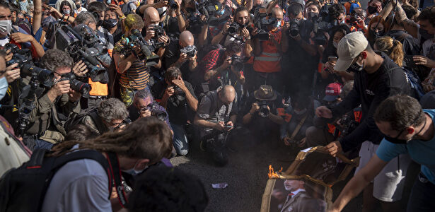 Imagen en la que se ve apenas un par de 'personas quemando una imagen del Rey rodeados de decenas de fotógrafos. (AP Photo/Emilio Morenatti) | Gtres