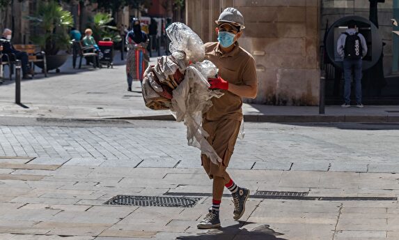 Trabajador de la construcción con equipo de protección caminando por una calle del centro de Barcelona durante el covid | Alamy