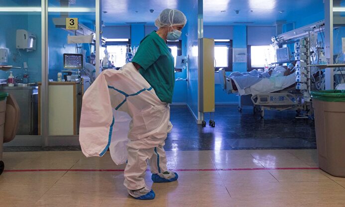 En la imagen, una enfermera del centro hospitalario se pone un mono de protección antes de entrar en el box de la UCI para atender a un paciente ingresado por COVID-19. | EFE