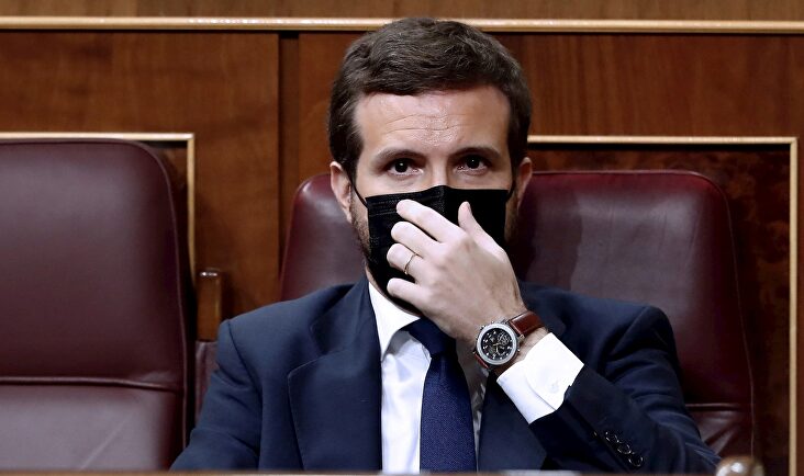 El líder del Partido Popular, Pablo Casado, se coloca la mascarilla mientras asisten a la moción de censura presentada por Vox al gobierno de coalición en el Congreso de los Diputados este miércoles | EFE