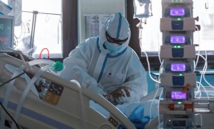 Sanitario atendiendo a una paciente de coronavirus en una UCI | EFE