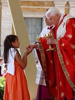 Benedicto XVI le ofrece el pan a una niña durante el encuentro con los movimientos