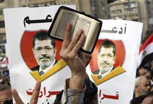 Un manifestante muestra El Corn ante dos pancartas de Mursi | EFE