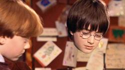 Harry Potter vistiendo (de cuello para abajo) la capa de invisibilidad en la primera película de la saga