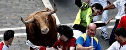Varios mozos pasan apuros ante uno de los toros de la ganadera Torrehandilla- Torreherberos durante el ltimo encierro de los sanfermines 2012 | EFE