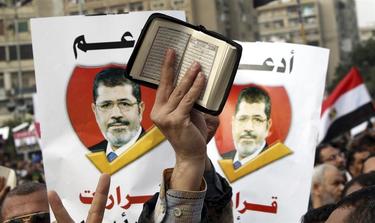 Un manifestante muestra El Corn ante dos pancartas de Mursi | EFE