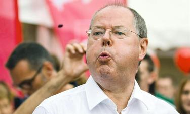 Steinbrück participando en un concurso de lanzamiento de huesos de cereza este domingo | EFE