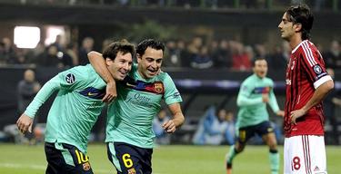 Xavi celebra junto a Messi su primer gol al Milan. | EFE
